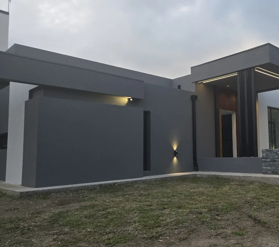 Fachada de Casa Causana al atardecer, con iluminación arquitectónica integrada en cada volumen