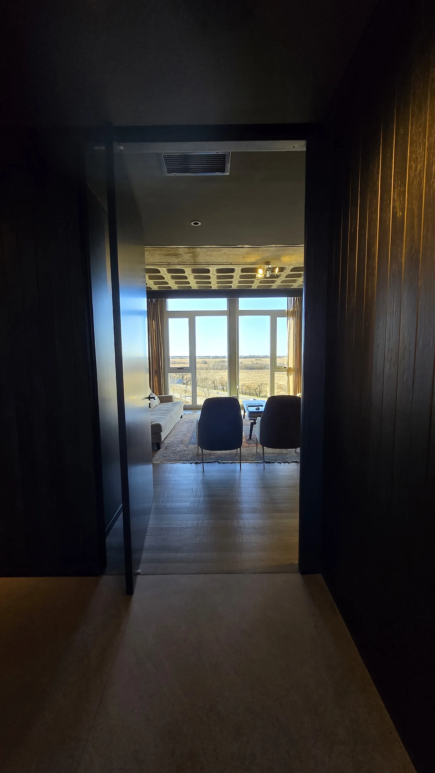Vista desde el pasillo de acceso hacia el living de la oficina Dracma, con ventanales de piso a techo