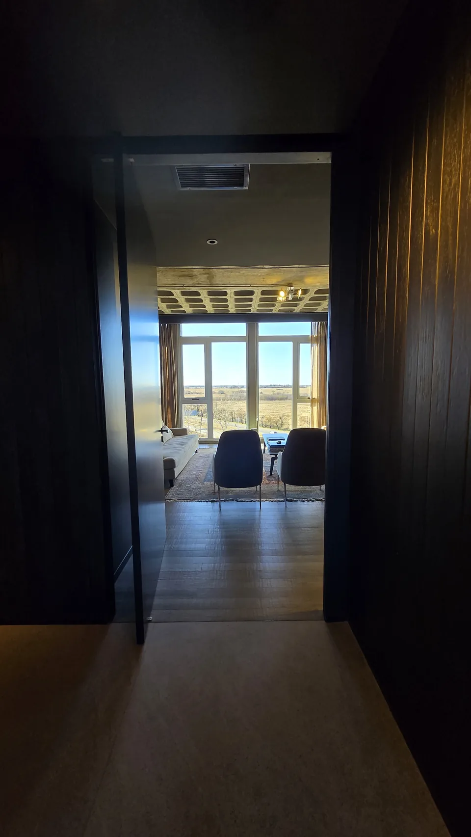 Vista desde el pasillo de acceso hacia el living de la oficina Dracma, con ventanales de piso a techo