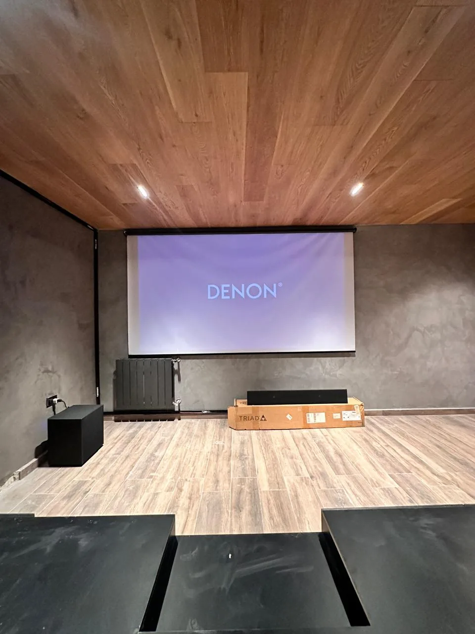 Home cinema en obra: pantalla de proyección, subwoofer y parlante de barra listos para instalar, con procesador Denon
