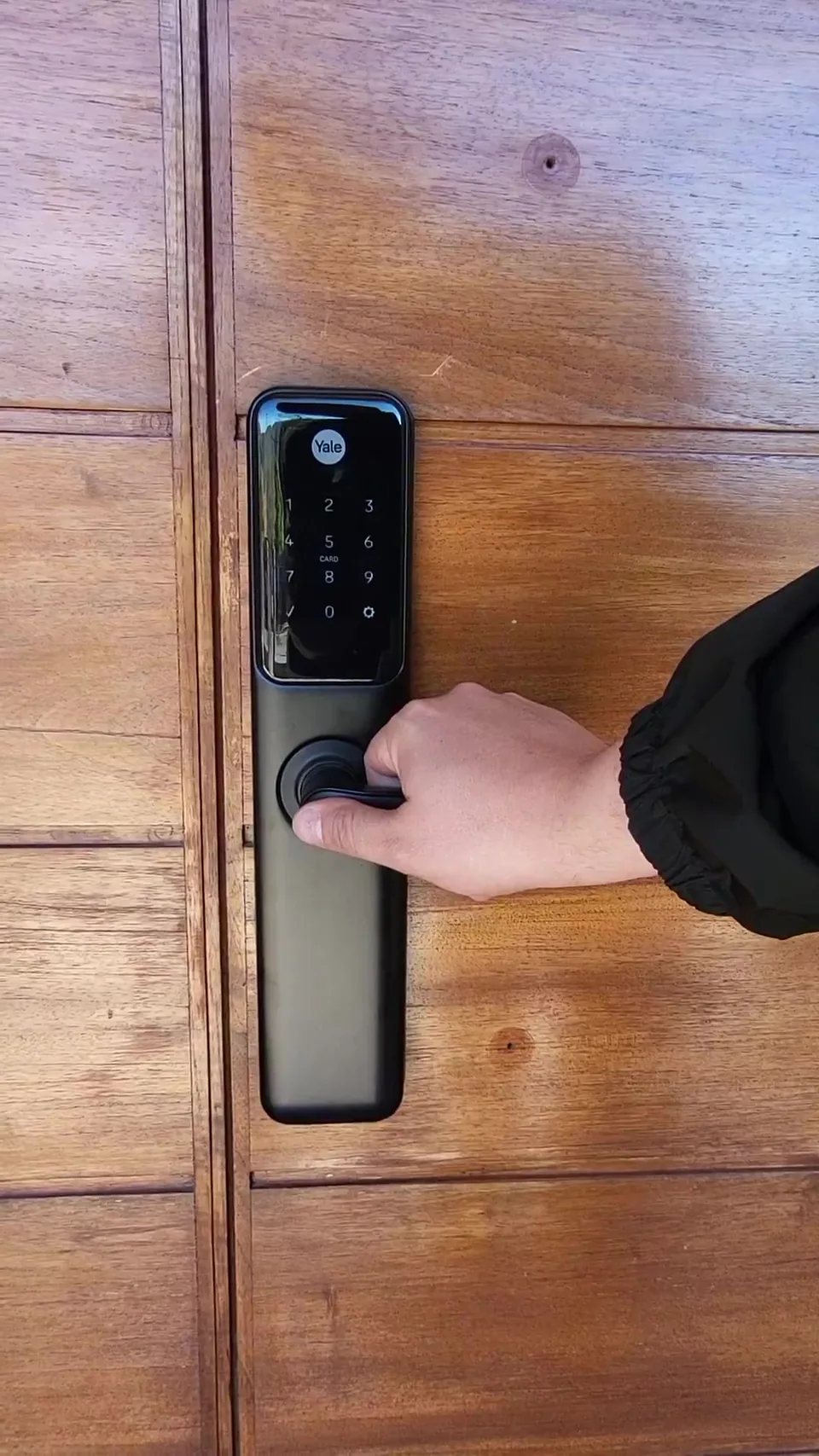 Cerradura digital Yale instalada en puerta de madera maciza, mano abriendo con la manija
