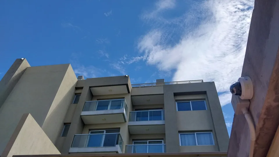Cámara de seguridad instalada en la esquina de una fachada, vista desde abajo